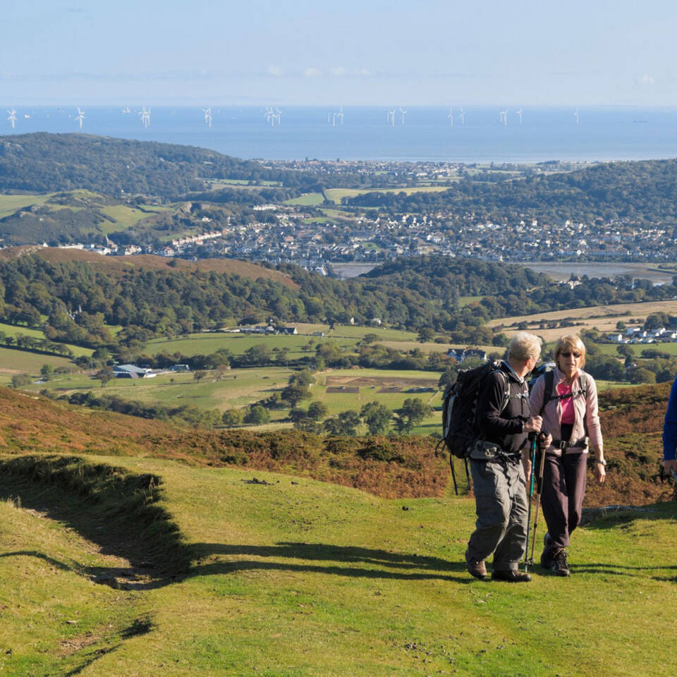 Local Area Walkers on path to Tal y Fan in Snowdonia National Park with coast in the distance Conwy North Wales Large